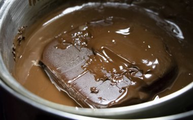 Su banyosunun altındaki bir tavada erimiş çikolata. Kendi mutfağında sıcak çikolata yapmak.