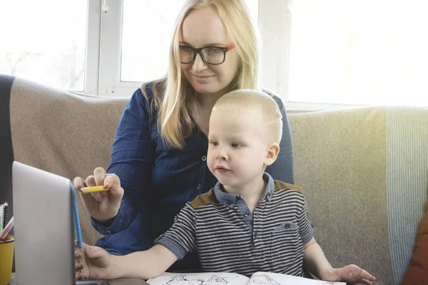 Mom and son do their homework, study online on the Internet. The concept of preschool education, home schooling of quarantined children during the coronovirus pandemic, covid-19