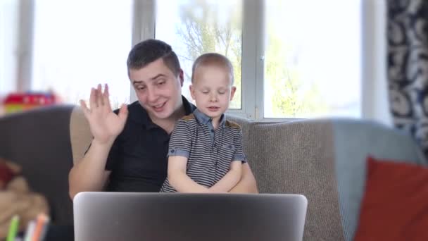 父と息子はノートパソコンを見ている 親戚とのビデオ通話 お父さんと息子の波 こんにちは ノートパソコンには 祖父母と話をし 会話の最後に合意の のような 表示されます 家庭における近代技術の概念 — ストック動画