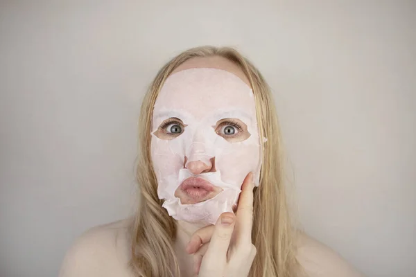 一个快乐而有趣的女孩带着润肤的面罩鬼鬼祟祟 晨美治疗 油性和混合性皮肤护理概念 — 图库照片