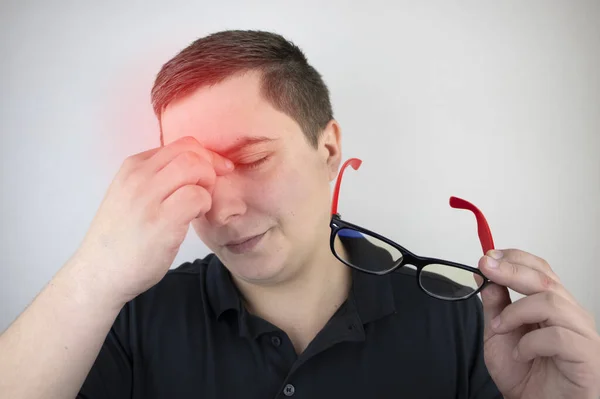 A man rubs his tired eyes with his hands on a white background. The concept of eye fatigue from the computer and fatigue from work. Pain in the eyes and forehead, migraine, eye diseases