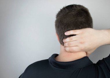 Bir adam boynundaki ağrıdan muzdarip, servikal omurgaya eliyle masaj yapıyor. Osteokondrosis, fıtık, ya da yerleşik iş ya da fiziksel stres kaynaklı sinir hasarı
