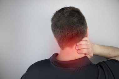 Bir adam boynundaki ağrıdan muzdarip, servikal omurgaya eliyle masaj yapıyor. Osteokondrosis, fıtık, ya da yerleşik iş ya da fiziksel stres kaynaklı sinir hasarı