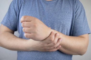 Erkek bileği acıtır. Travmatolog el muayenesi yapıyor. Bilek ağrısı tünel sendromu, burkulma, tendon dejenerasyonu, eklem iltihabı belirtisi.
