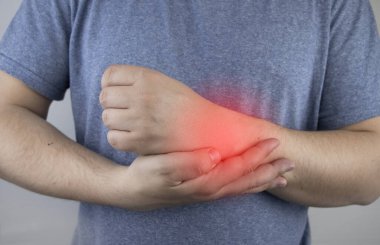 Erkek bileği acıtır. Travmatolog el muayenesi yapıyor. Bilek ağrısı tünel sendromu, burkulma, tendon dejenerasyonu, eklem iltihabı belirtisi.