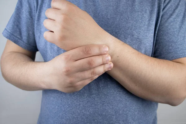 Erkek bileği acıtır. Travmatolog el muayenesi yapıyor. Bilek ağrısı tünel sendromu, burkulma, tendon dejenerasyonu, eklem iltihabı belirtisi.