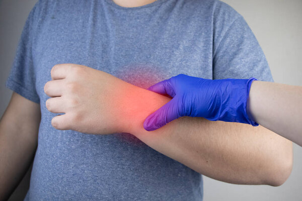 Мужское запястье болит. Травматолог осматривает руку. Боль в запястье как признак туннельного синдрома или растяжения, дегенерации сухожилий, артрита
