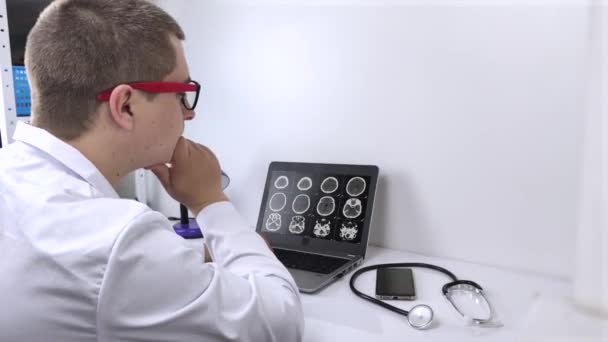 放射線医は コンピュータモニタ上で脳の計算断層撮影の結果を調べます 神経疾患および腫瘍疾患の診断 — ストック動画