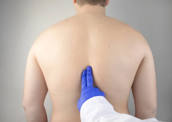 Pain in the spine. A man at the doctors appointment with a neurologist and vertebrologist. Diseases of the back, pinched nerve, intervertebral hernia, or osteochondrosis