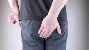 A man holds his hands to the ass feeling pain. Conversion of pain in the rectum, hemorrhoids and pain in the excretory system of the body. Frequent bowel movements.