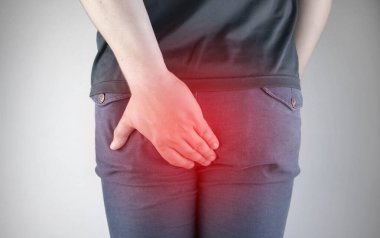 A man holds his hands to the ass feeling pain. Conversion of pain in the rectum, hemorrhoids and pain in the excretory system of the body. Frequent bowel movements.