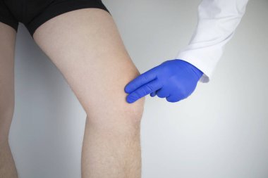 Bir adam diz ağrısından muzdarip. Bir ortopedist ve travmatolog tarafından muayene. Bacaklarda kızarıklık ve şişkinlik, menisküs yırtılması veya diz kesesi iltihabı.