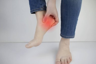 Woman suffering from heel pain. Inflammation or sprain of the tendon in the foot, heel spur, bursitis. The concept of diseases and pains in the leg clipart