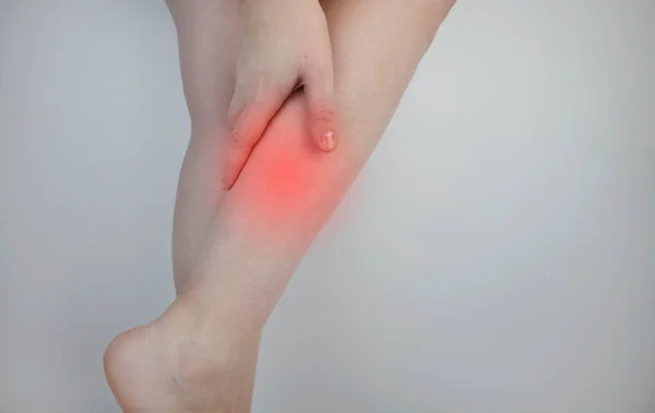 A woman suffers from pain in the calves. Stretching the calf muscle, varicose veins, leg cramps, or myositis. Orthopedic doctor examines patient — Stock Image Woman Suffers Pain Calves Stretching Calf Muscle Varicose Veins Leg Royalty Free Stock Images