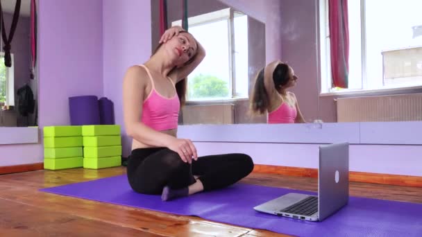 健身和瑜伽教练通过笔记本电脑授课 体育运动中的无线技术 这个女孩在体育馆的垫子上做运动 远距离学习的概念 — 图库视频影像