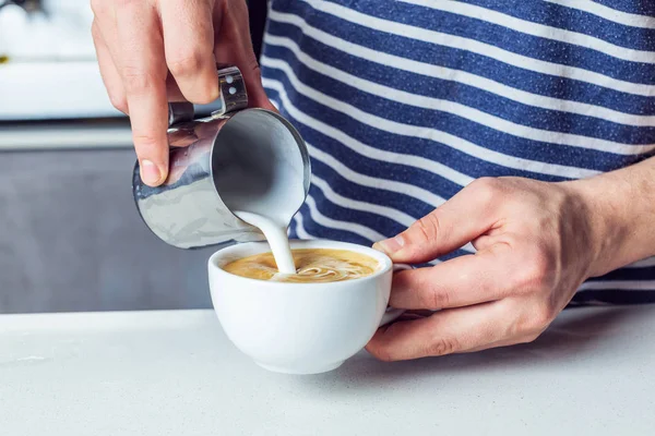 Человек наливает молоко в кофе — стоковое фото