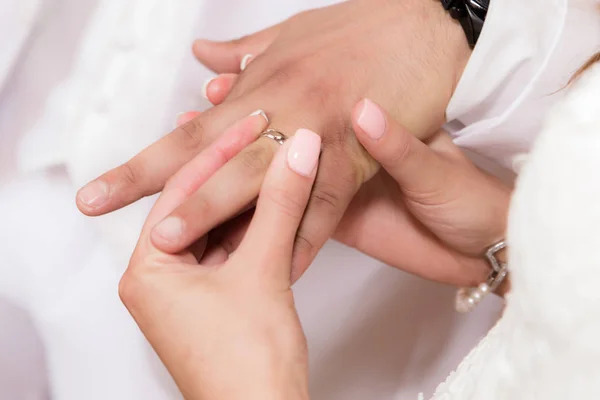 Feche mãos de noiva e noivo pondo umas alianças de casamento — Fotografia de Stock