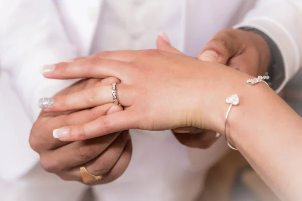 Feche mãos de noiva e noivo pondo umas alianças de casamento — Fotografia de Stock