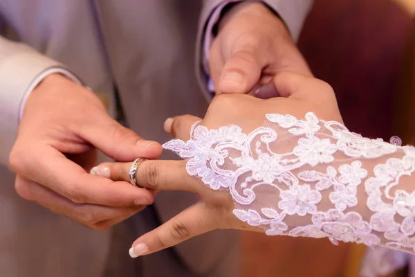 Feche mãos de noiva e noivo pondo umas alianças de casamento — Fotografia de Stock