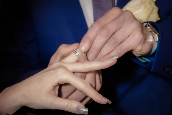 Закройте руки жениху и невесте надевая обручальные кольца — стоковое фото