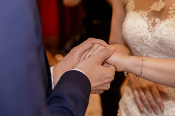 Feche mãos de noiva e noivo pondo umas alianças de casamento — Fotografia de Stock