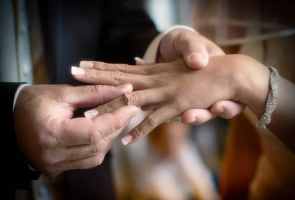 Feche mãos de noiva e noivo pondo umas alianças de casamento — Fotografia de Stock