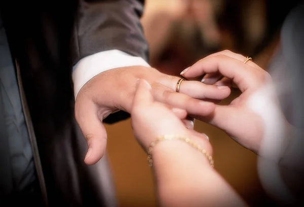 Feche mãos de noiva e noivo pondo umas alianças de casamento — Fotografia de Stock