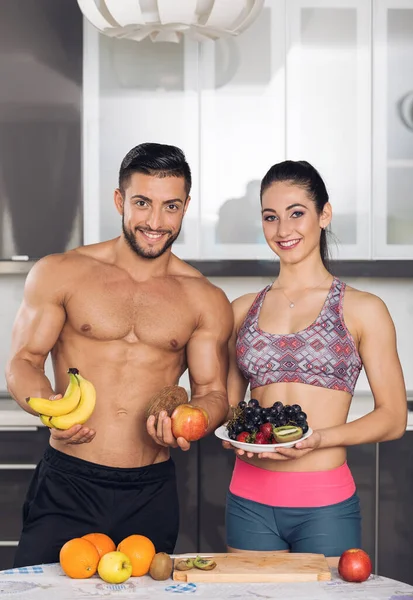 Young Fit Couple Kitchen Holding Fruits Banana Apple Grapes Strawberry — Stock Photo, Image