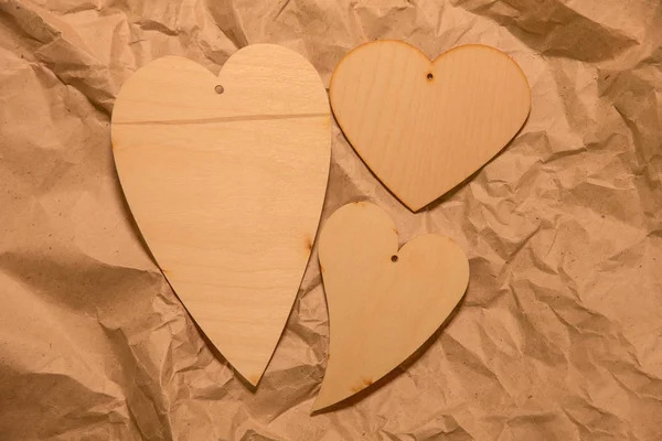 Corazones de madera sobre papel kraft arrugado —  Fotos de Stock