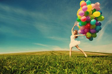 mutlu yıllar kadın elinde gökkuşağı renginde hava balonu gökyüzüne karşı. güneşli ve pozitif enerji doğa. genç güzel kız parkta çim.