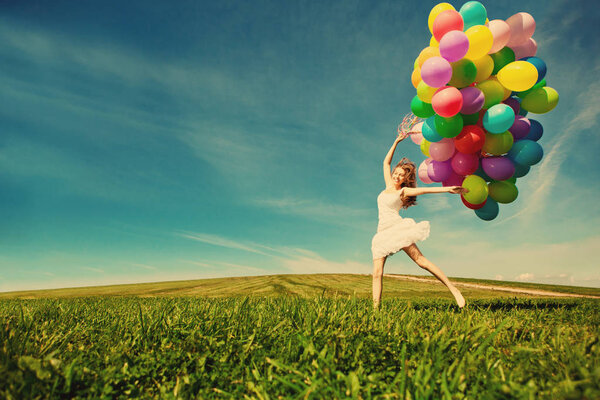 С днем рождения женщина против неба с радужными воздушными шарами в руках. солнечная и позитивная энергия природы. Молодая красивая девушка на траве в парке
.