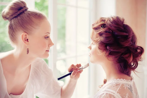 Stylist makes makeup bride before the wedding