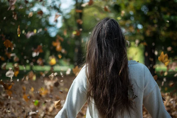 Sonbaharda düşen yaprakları arasında parkta uzun saçlı kız