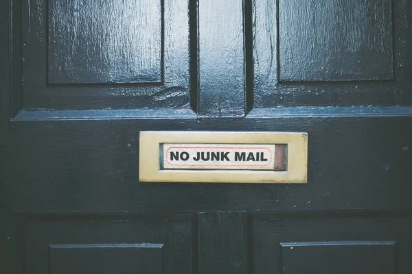 No Junk mail sign metal plate on a black door.