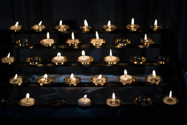 Lit up votive candles lighten the dark in a church