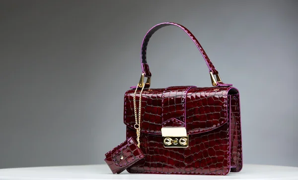 Gri arka plan üzerinde izole kırmızı parlak kadın deri çanta