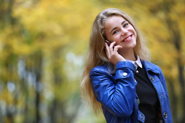Cep telefonu ile sonbahar parkta genç kız