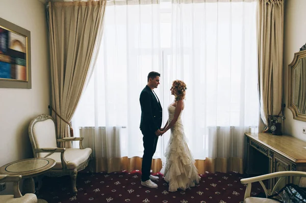 Bruid en bruidegom hand in hand op kamer — Stockfoto
