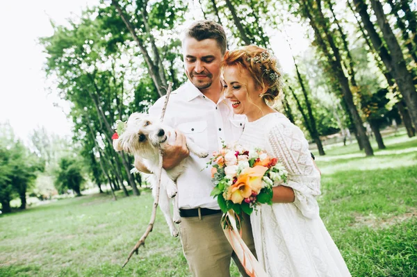 Bruden och brudgummen med hund i händer — Stockfoto