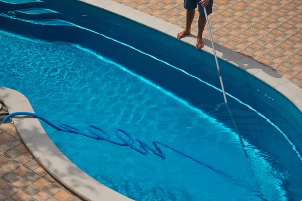 Mann reinigt Schwimmbad mit Staubsauger — Stockfoto