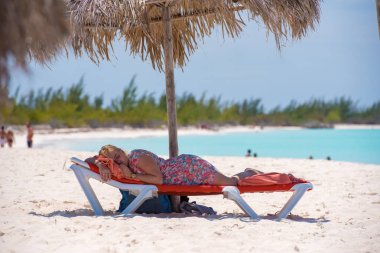Cayo Largo, Küba - 10 Mayıs 2017: Bir kadın bir şemsiye altında bir şezlong üzerinde uyuyor. Metin için yer kopyalayın.