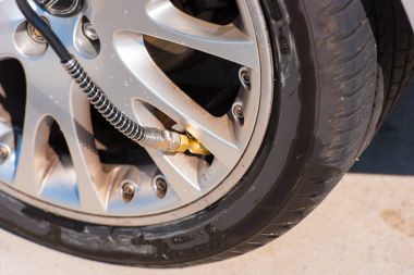 Checking tire pressure. Pumping air into auto wheel. Close-up. clipart