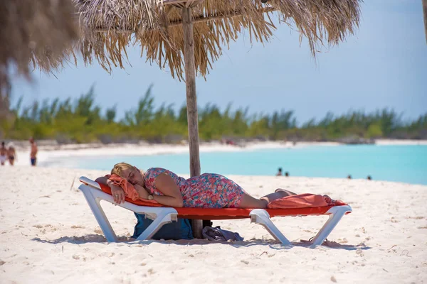 Cayo Largo, Küba - 10 Mayıs 2017: Bir kadın bir şemsiye altında bir şezlong üzerinde uyuyor. Metin için yer kopyalayın.