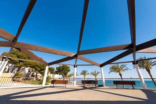 A small wooden pavilion with benches on the waterfront in L\'Hospitalet de l\'Infant, Tarragona, Catalunya, Spain. Copy space