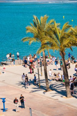 Salou, Tarragona, İspanya - 24 Nisan 2017: Turist Costa Dorada sahilinde palmiye ağaçlarının altında. Dikey.