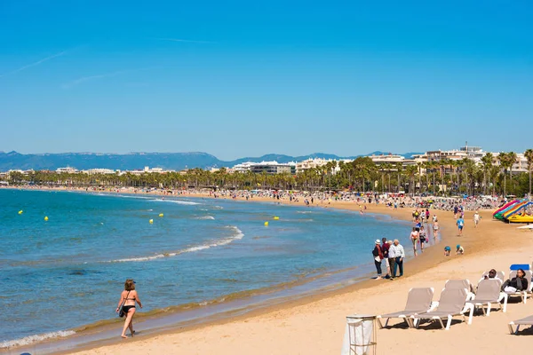 SALOU, TARRAGONA, ESPANHA - 24 de abril de 2017: Pessoas caminhando ao longo da praia da Costa Dorada. Céu azul. Espaço de cópia para texto . — Fotografia de Stock