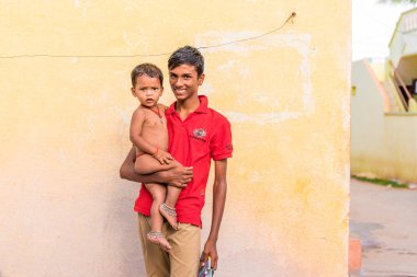 Puttaparthi, Andhra Pradesh, Hindistan - 9 Temmuz 2017: Hint adam onun kollarında bir bebekle. Metin için yer kopyalayın.