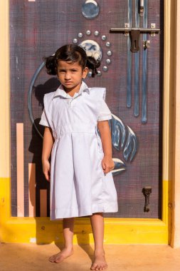 Puttaparthi, Andhra Pradesh, Hindistan - 9 Temmuz 2017: Sevimli Hintli kız beyaz elbiseli. Dikey. Metin için yer kopyalayın.