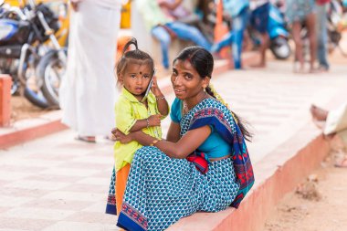 PUTTAPARTHI, ANDHRA PRADESH, INDIA - JULY 9, 2017: Little Indian girl on walk with mum. Copy space for text. clipart