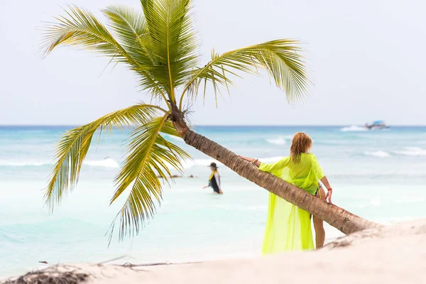 SAONA, REPÚBLICA DOMINICANA - 25 DE MAYO DE 2017: Una mujer cerca de una palmera en una playa de arena. Copiar espacio para texto . — Foto de Stock